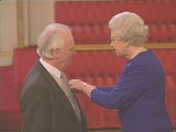 Photo of John receiving MBE from HM The Queen